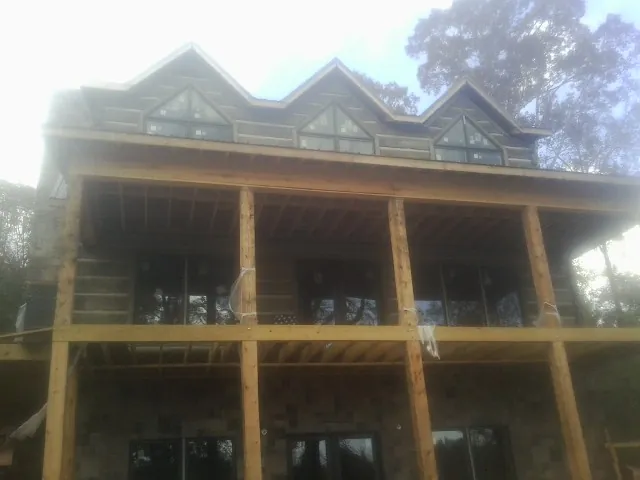 Dormers and porch framing on a large log home under construction — Roof Coating work by our crew in Salem
